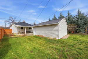 Back of property featuring a fenced backyard, a patio, an outdoor structure, and roof with shingles