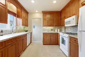 Kitchen featuring white appliances, tile countertops, wood finish cabinets, light tile patterned floors, and recessed lighting