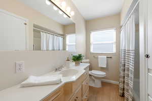 Full bath with vanity, a shower with curtain, and light wood finished floors