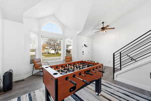 Recreation room featuring vaulted ceiling, ceiling fan, and light wood finished floors