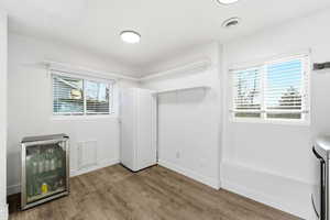 Laundry room with wine cooler and wood finished floors