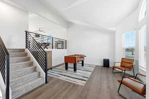 Rec room with vaulted ceiling, light wood-style flooring, and ceiling fan