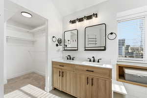 Bathroom with double vanity, a spacious closet, and light carpet