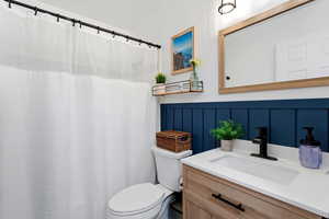 Full bathroom with vanity, a shower with shower curtain, and a decorative wall