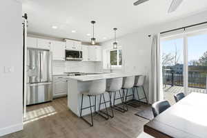 Kitchen featuring a breakfast bar area, a peninsula, stainless steel appliances, and white cabinetry
