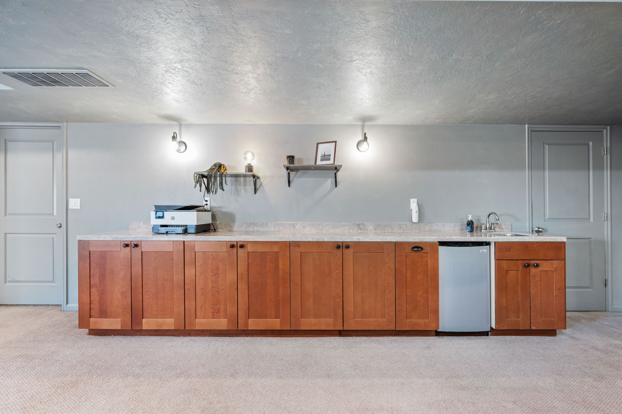 Kitchen with a textured ceiling, light carpet, wood finish cabinetry, dishwasher, and open shelves
