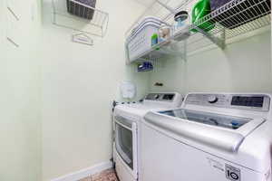 Laundry room with washer and clothes dryer and light tile patterned floors