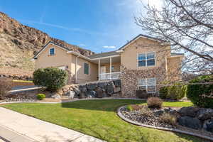 View of front of home with stucco siding, a front lawn, a garage, a mountain view, and covered porch