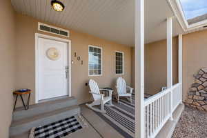 Entrance to property featuring covered porch and stucco siding