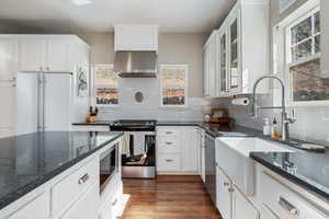 Kitchen featuring stainless steel appliances, white cabinetry, and dark stone counters