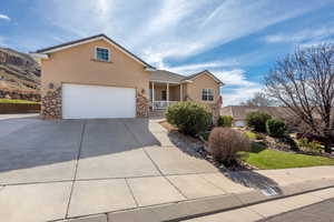 Traditional-style home featuring stucco siding, stone siding, concrete driveway, and covered porch
