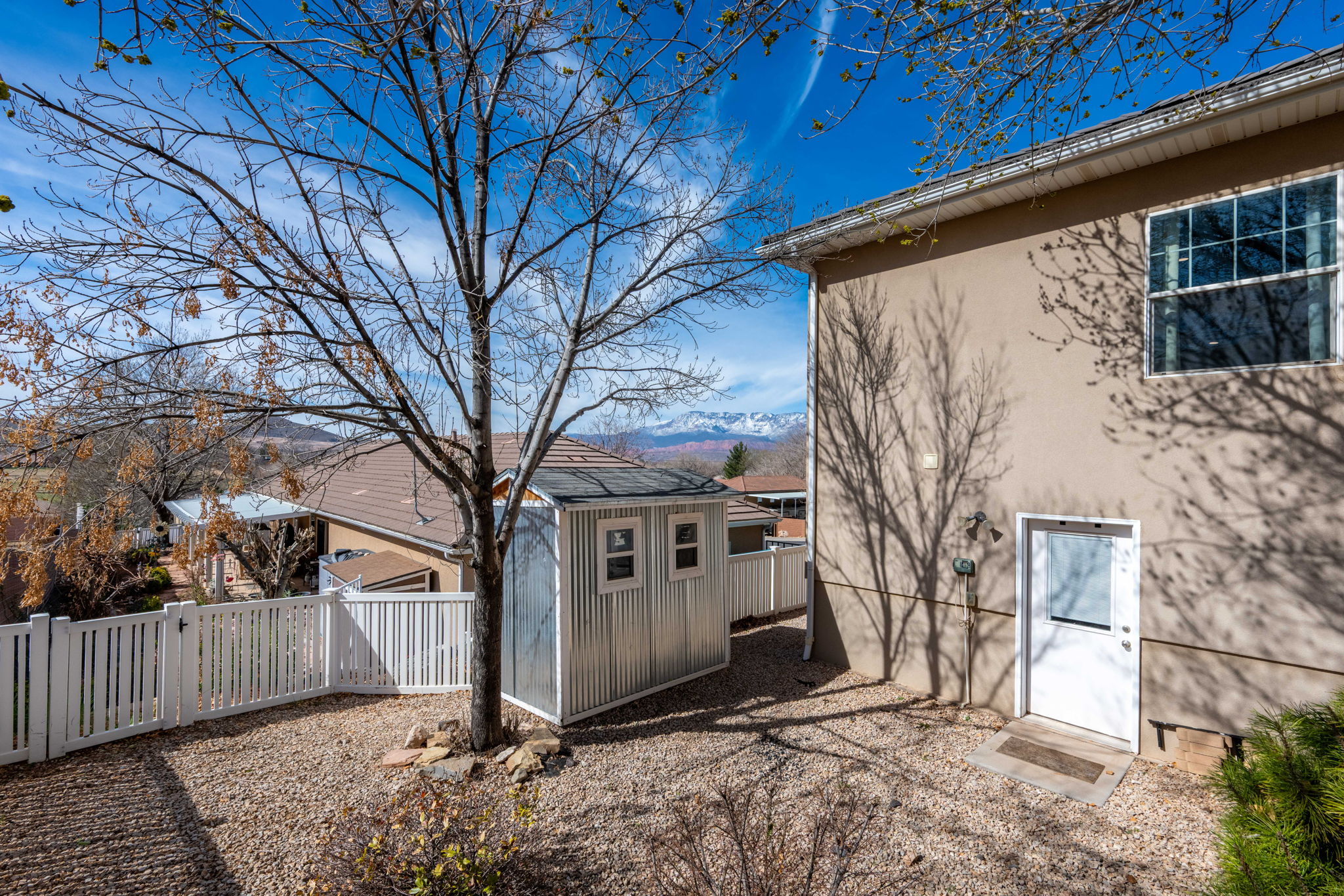 Rear exterior featuring a stucco finish, white frame window, and a white entry door