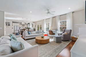 Living room with dark wood-type flooring, a ceiling fan, and recessed lighting