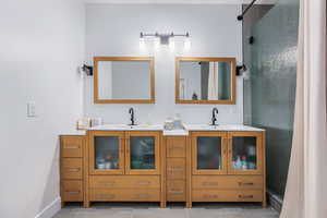 Bathroom featuring double vanity, a stall shower, and light tile patterned floors