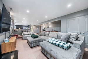 Living area with light colored carpet and recessed lighting