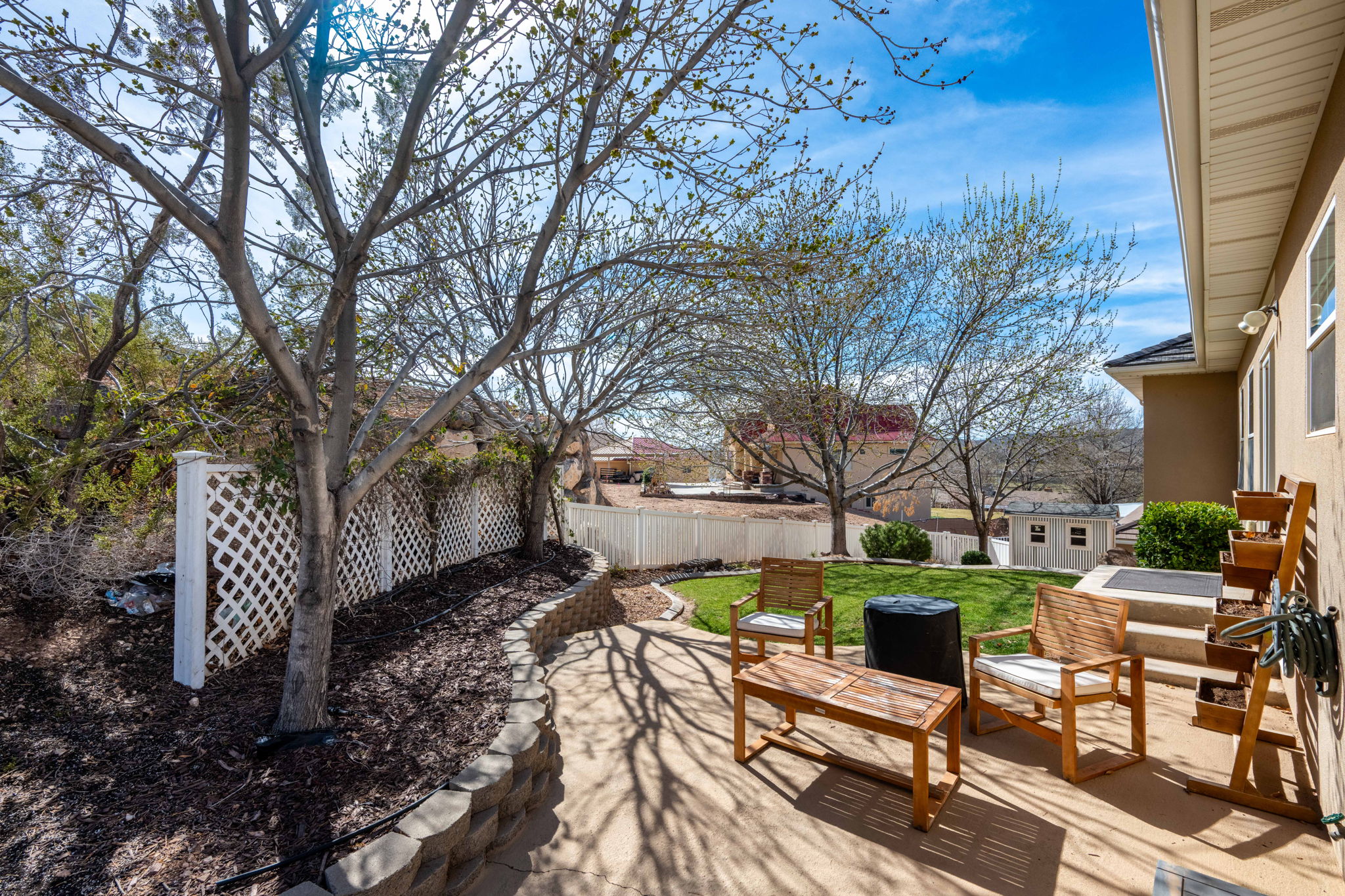Expansive outdoor patio featuring concrete paving, a tiered retaining wall, and a white lattice fence