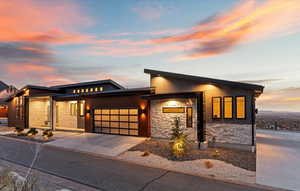 View of front of property with a garage, concrete driveway, and stone siding