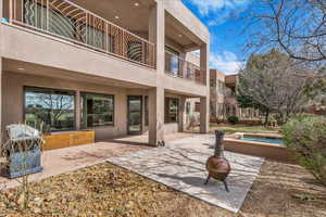 Rear view of house featuring a patio, stucco siding, a balcony, and an outdoor fire pit