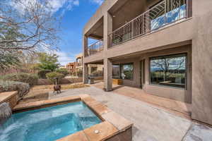 View of pool featuring patio surround, a balcony, a pool, and an in-ground hot tub