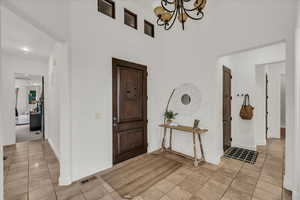 Foyer entrance with hanging lights, light tile patterned floors, and a high ceiling