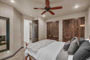 Bedroom featuring two closets, light colored carpet, a ceiling fan, and recessed lighting