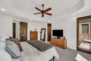 Bedroom with recessed lighting, light colored carpet, a tray ceiling, and ceiling fan