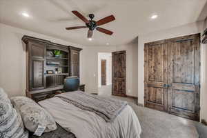 Carpeted bedroom with a ceiling fan and recessed lighting