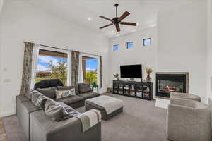 Living room featuring a high ceiling, ceiling fan, a tile fireplace, light carpet, and recessed lighting