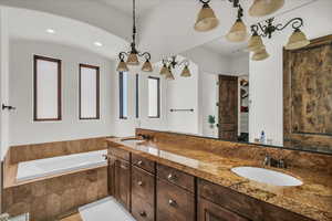 Bathroom featuring a garden tub, double vanity, and recessed lighting