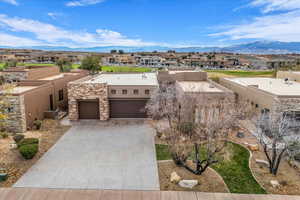 Southwest-style home with an attached garage, driveway, a mountain view, and a residential view