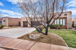 View of front facade featuring driveway, stone siding, a garage, stucco siding, and a front lawn