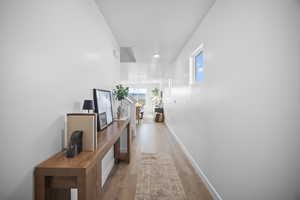 Hallway with light wood-style floors and recessed lighting