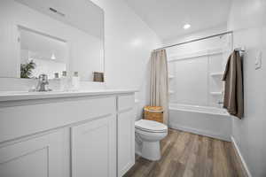Full bathroom with vanity, dark wood-type flooring, shower / tub combo, and recessed lighting