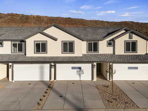 All photos are of similar home.  View of front of home with stucco siding, an attached garage, a shingled roof, and concrete driveway