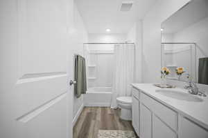 Full bathroom with vanity, dark wood-style flooring, and shower / bath combo with shower curtain