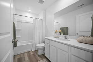 Full bath with vanity, dark wood finished floors, and shower / tub combo