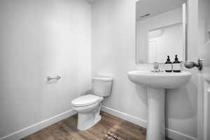 Half bath with toilet and wood finished floors