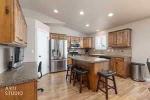 Kitchen featuring a breakfast bar area, dark countertops, a kitchen island, and stainless steel appliances