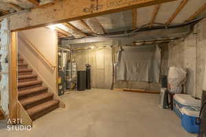 Unfinished basement featuring a water softener system, water heater, and heating unit
