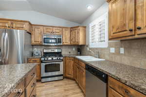 Kitchen featuring stainless steel appliances, wood finish cabinetry, wood floors, and decorative backsplash