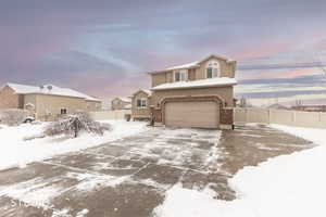 Snowy View of front of home featuring driveway, an attached garage, and brick siding showing RV pad on right.