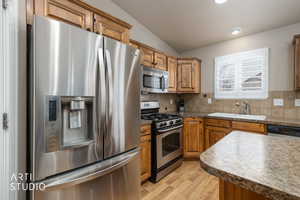 Kitchen featuring stainless steel appliances, light wood finished floors, tasteful backsplash, and wood finish cabinets
