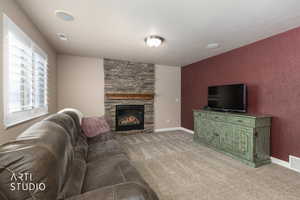 Family room with carpet and stone fireplace