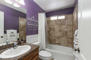 Bathroom featuring a wainscoted wall, vanity, and shower / bath combo with shower curtain