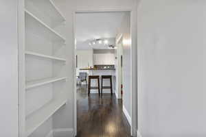 Hallway featuring dark wood-style floors and baseboards