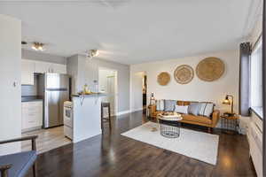 Living room with dark wood-type flooring and baseboards