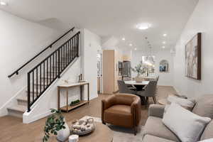Living room with light wood-type flooring, hanging lights, and a textured ceiling