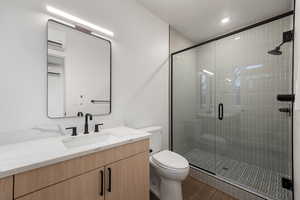Full bath featuring vanity, a stall shower, dark wood finished floors, and a textured ceiling