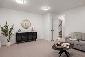 Carpeted living area featuring baseboards and a textured ceiling