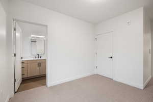 Unfurnished bedroom with light carpet and ensuite bathroom